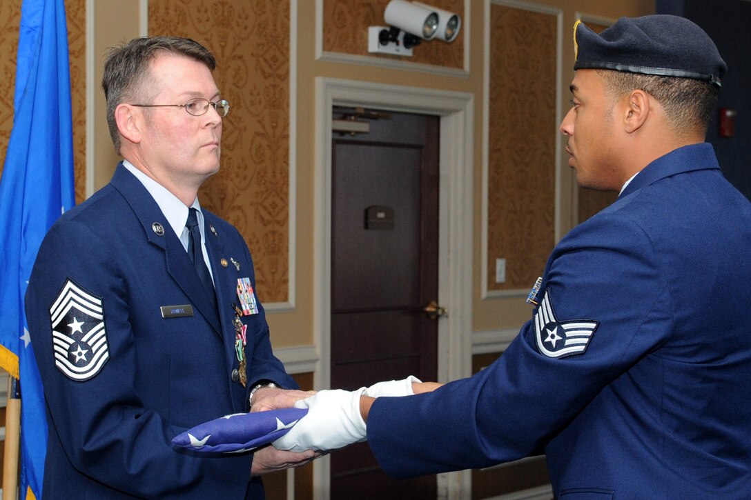 U.S. Air Force Chief Master Sgt. Kevin Howell (left), 633rd Air Base Wing command chief, receives a ceremonial retirement flag from Staff Sgt. Maurice Carter, 633rd Security Forces Squadron assistant flight chief, during a retirement ceremony at Langley Air Force Base, Va., June 15, 2012. Howell served more than 29 years in various positions, including surveillance operator, instructor weapons director, squadron and group superintendent, as well as Air Combat Command director of operations. (U.S. Air Force Photo by Airman 1st Class Racheal Watson/Released)