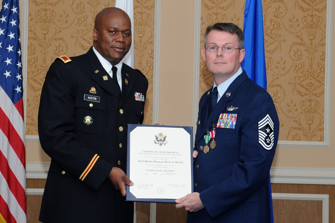 U.S. Army Col. Reggie Austin, 633rd Air Base Wing vice commander, holds the decorative certificate with U.S. Air Force Chief Master Sgt. Kevin Howell, 633 ABW command chief, during a retirement ceremony at Langley Air Force Base, Va., June 15, 2012. Howell served more than 29 years of dedicated service through a variety of assignments in tactical ground and air operations, including deployments to Operations Northern and Southern Watch, Operation Iraqi Freedom, Operation Enduring Freedom, U.S. Southern Command Counter Drug Operations and Combined Joint Task Force–Horn of Africa. (U.S. Air Force Photo by Airman 1st Class Racheal Watson/Released)