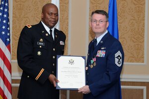 U.S. Army Col. Reggie Austin, 633rd Air Base Wing vice commander, holds the decorative certificate with U.S. Air Force Chief Master Sgt. Kevin Howell, 633 ABW command chief, during a retirement ceremony at Langley Air Force Base, Va., June 15, 2012. Howell served more than 29 years of dedicated service through a variety of assignments in tactical ground and air operations, including deployments to Operations Northern and Southern Watch, Operation Iraqi Freedom, Operation Enduring Freedom, U.S. Southern Command Counter Drug Operations and Combined Joint Task Force–Horn of Africa. (U.S. Air Force Photo by Airman 1st Class Racheal Watson/Released)