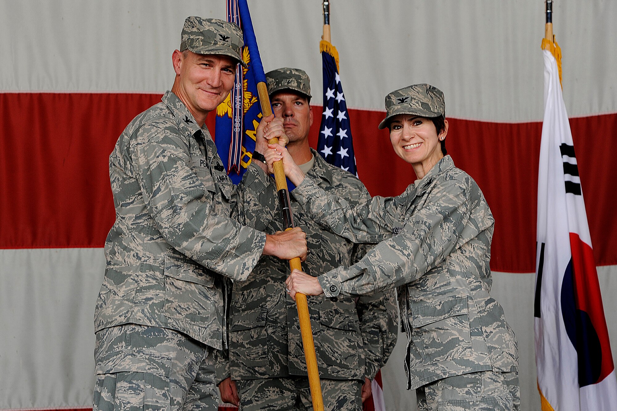 Col. John Pearse, 8th Fighter Wing commander, hands the 8th Medical Group guidon to Col. Jill Scheckel, new 8th MDG commander, during a change of command ceremony at Kunsan Air Base, Republic of Korea, June 15, 2012. Scheckel is the wing’s newest “Hawk.”(U.S. Air Force photo/Staff Sgt. Rasheen A. Douglas)