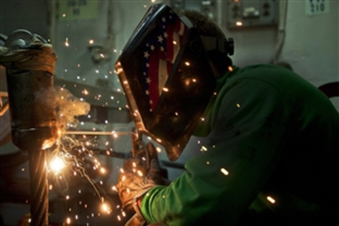 U.S. Navy Petty Officer 3rd Class Devin McMaster welds an anchor terminal on an arresting gear cable while conducting maintenance aboard the aircraft carrier USS George Washington under way in the Pacific Ocean, June 16, 2012. 