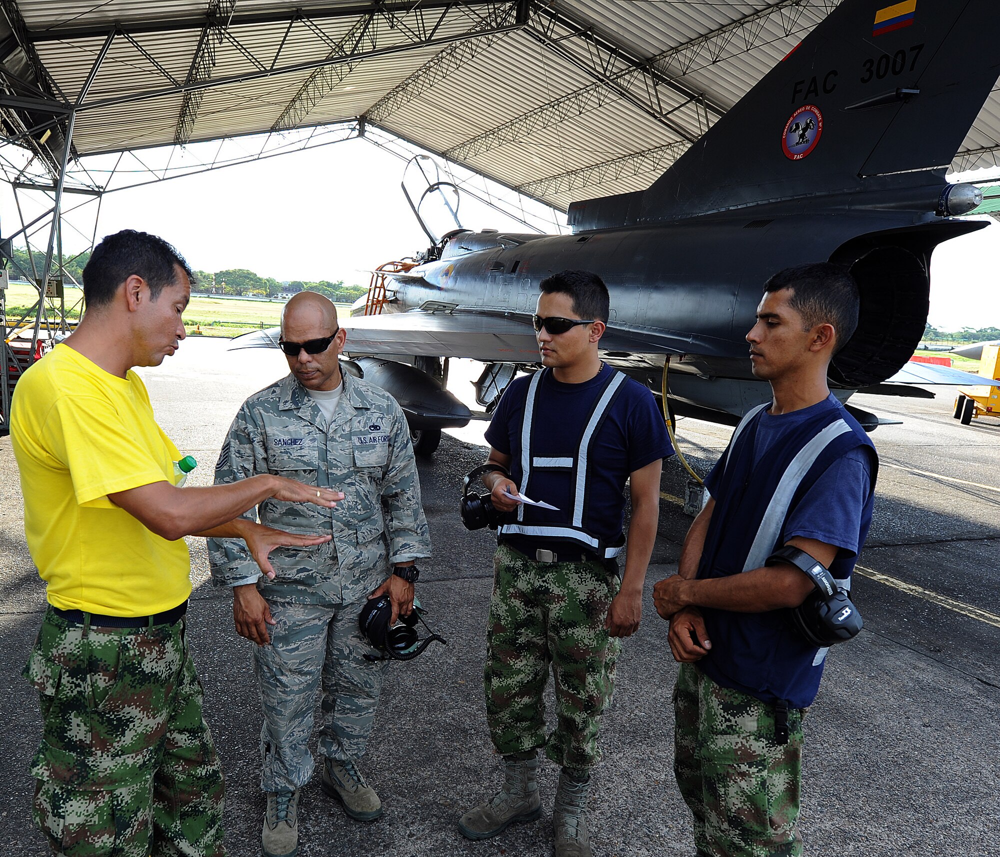 A Colombian air force crew chief explains to Tech. Sgt. Luis Sanchez, 571st MSAS aircraft maintenance air advisor, their aircraft launching procedures and communications with MOC prior to the evening's flights June 15, at Comando Aéreo de Combate No. 1 base, Palanquero, Colombia, as part of a month-long Air Mobility Command Building Partner Capacity mission. (U.S. Air Force photo by Tech. Sgt. Lesley Waters)