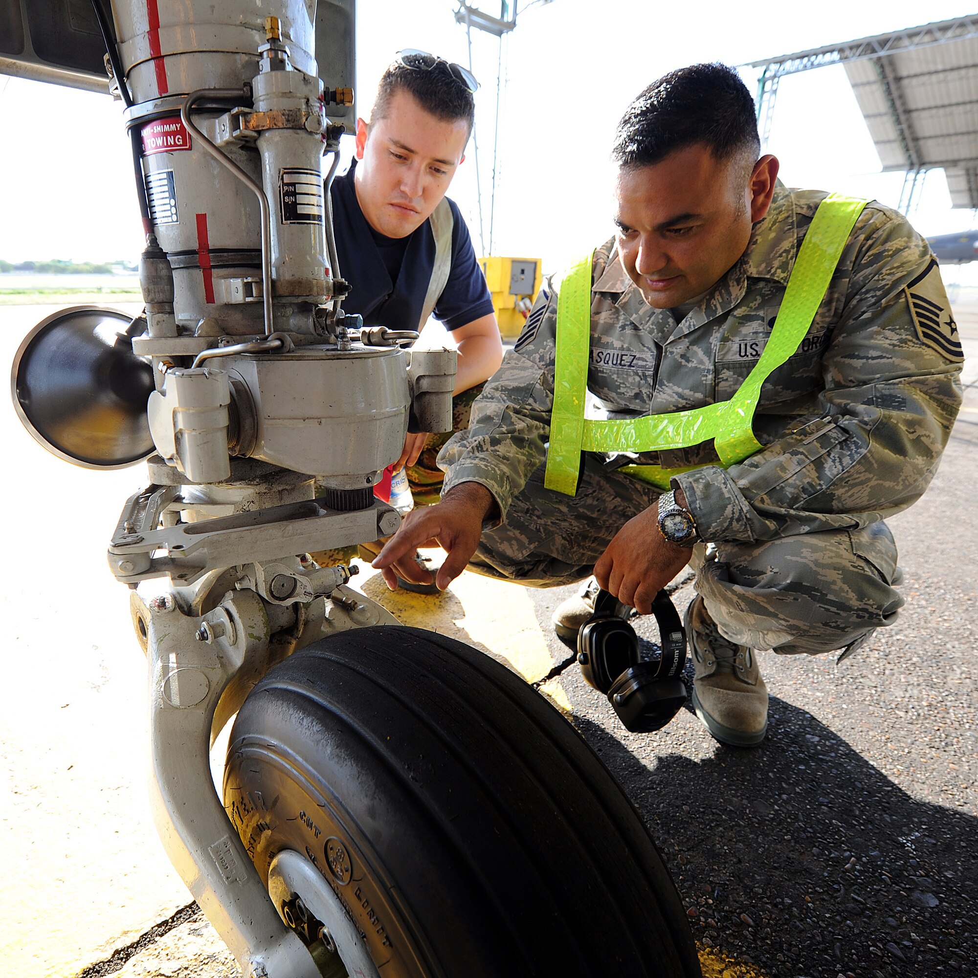 Master Sgt. Roberto Vasquez, 12th AF (AFSOUTH) heavy aircraft manager, and a Colombian crew chief inspect the wheels on a KFIR aircraft prior to take-off June 15, at Comando Aéreo de Combate No. 1 base, Palanquero, Colombia, as part of a month-long Air Mobility Command Building Partner Capacity mission. (U.S. Air Force photo by Tech. Sgt. Lesley Waters)