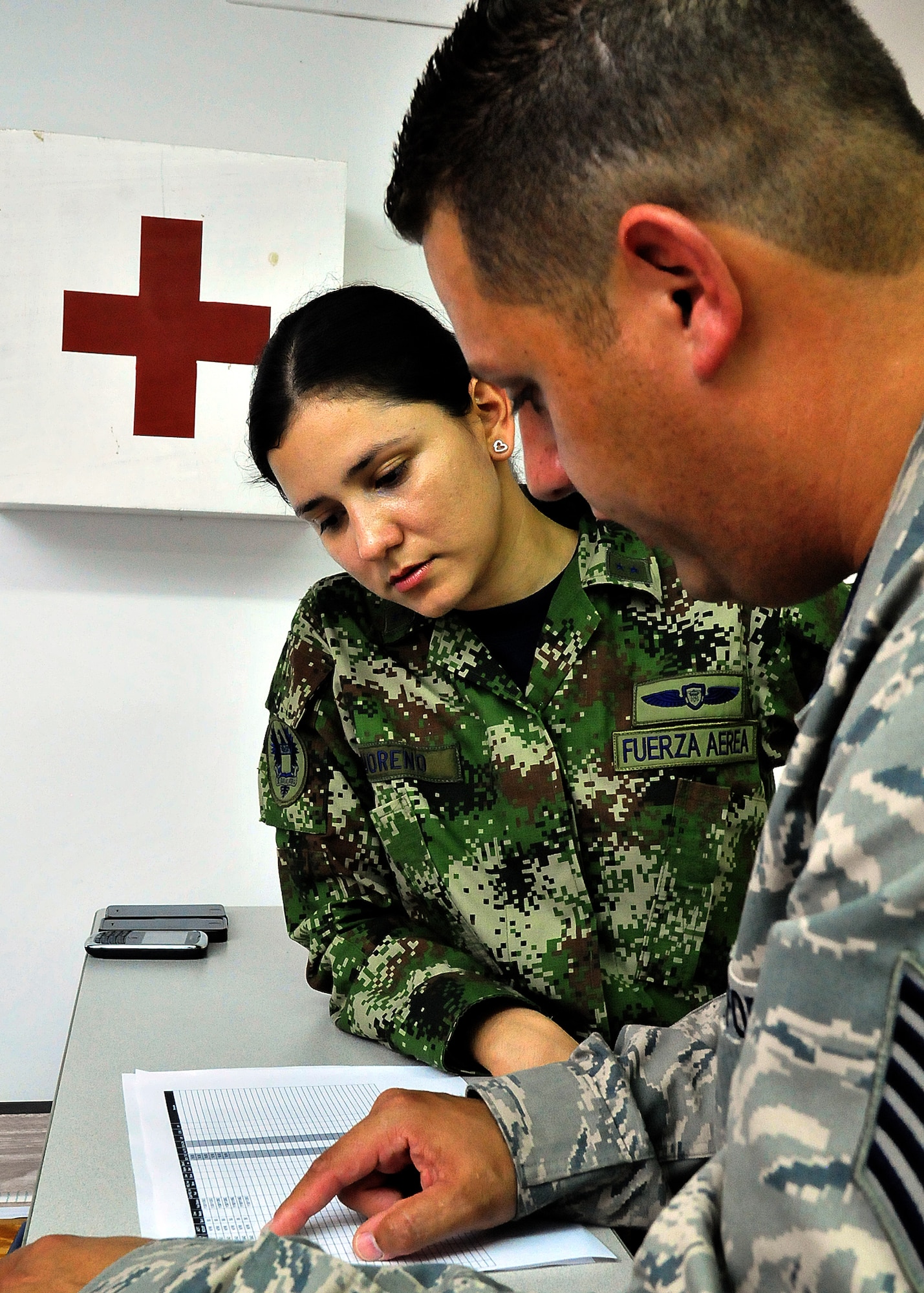 Technical Sgt. Melvin Rosario, Inter-American Air Forces Academy instructor, explains to 1st Lt. Mayra Moreno, CACOM-1 maintenance officer, how to read the evening's flight plan June 15, at Comando Aéreo de Combate No. 1 base, Palanquero, Colombia, as part of a month-long Air Mobility Command Building Partner Capacity mission. (U.S. Air Force photo by Tech. Sgt. Lesley Waters)