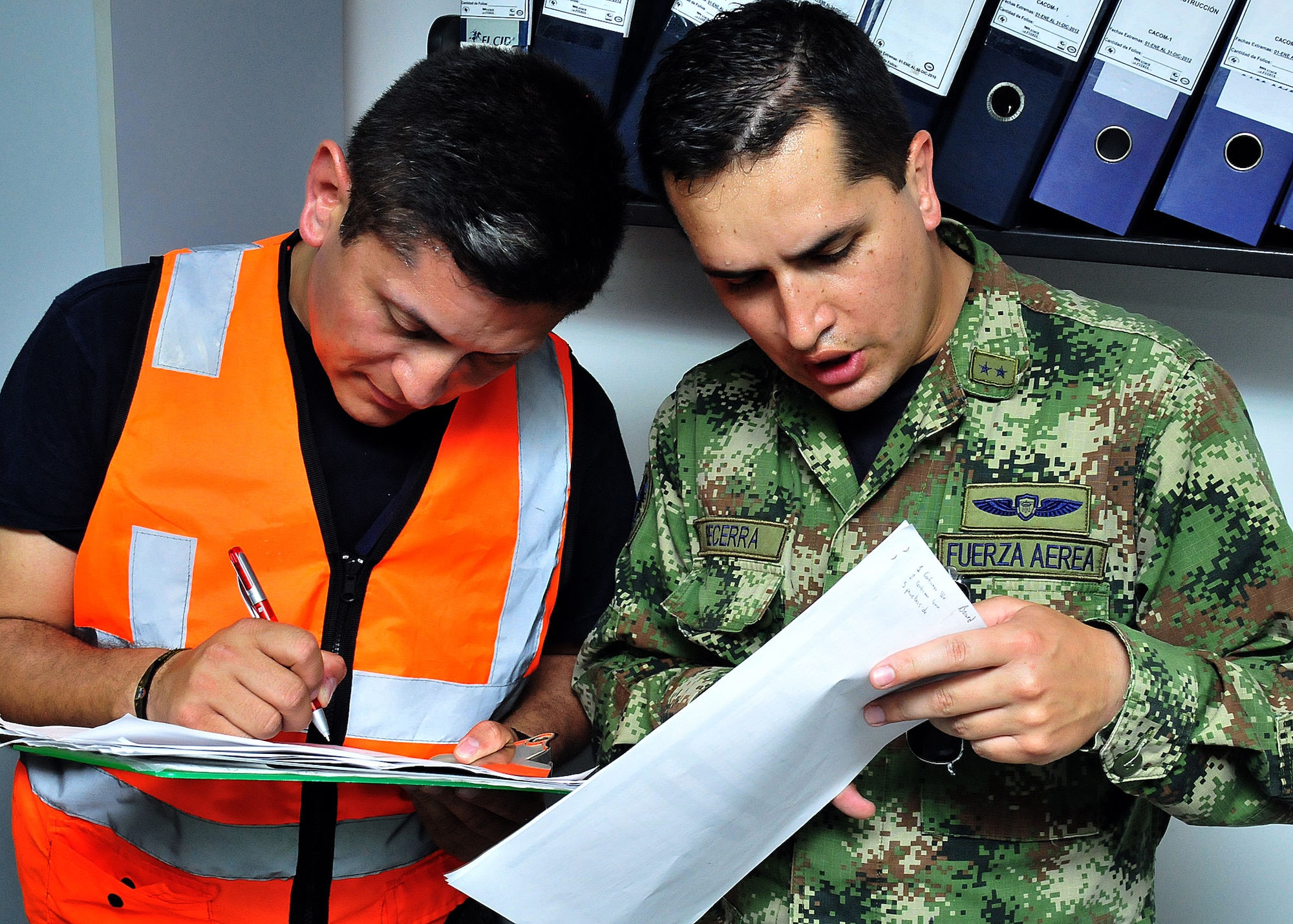 The production superintendent and a maintenance operations center member go over the evening's flight schedule before the MOC briefing for senior leadership June 15, at Comando Aéreo de Combate No. 1 base, Palanquero, Colombia, as part of a month-long Air Mobility Command Building Partner Capacity mission. (U.S. Air Force photo by Tech. Sgt. Lesley Waters)