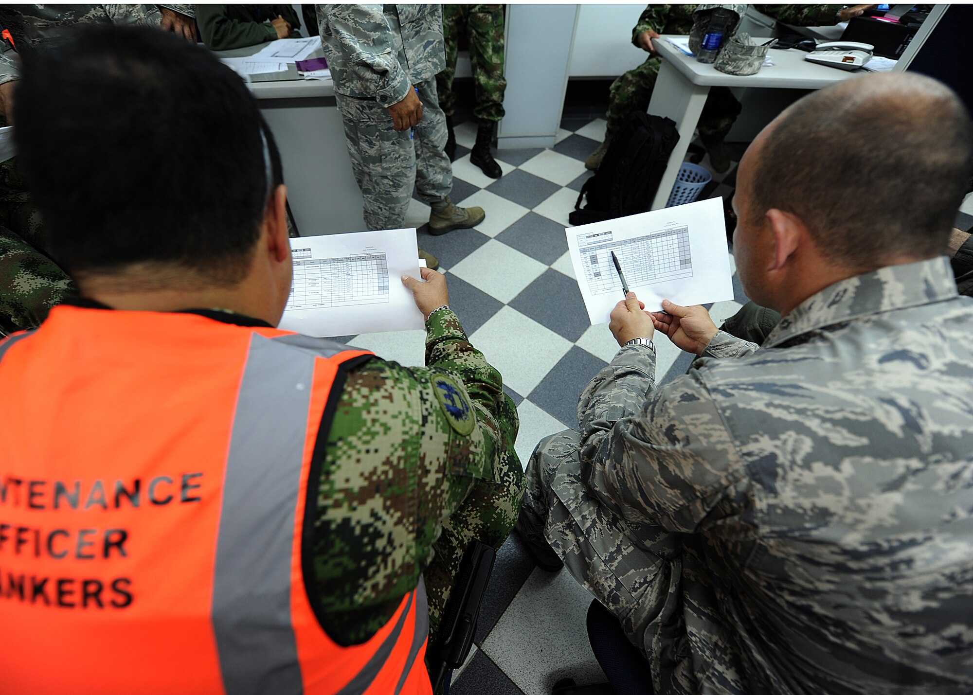 Major Carlos Gutierrez, Colombian air force Centro Administrativa Nacional Logistics officer, and Maj. Brian Symon, 571st MSAS Colombia mission commander, look over the Colombian air force aircraft status report during the maintenance operations center briefing for senior leadership June 14, at Comando Aéreo de Combate No. 1 base, Palanquero, Colombia, as part of a month-long Air Mobility Command Building Partner Capacity mission. (U.S. Air Force photo by Tech. Sgt. Lesley Waters)