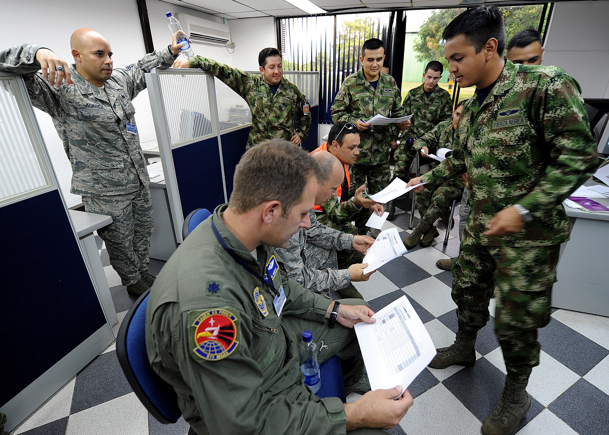 A Colombian air force member hands out the flight plan for the evening operations during the maintenance operations center briefing for senior leadership June 14, at Comando Aéreo de Combate No. 1 base, Palanquero, Colombia, as part of a month-long Air Mobility Command Building Partner Capacity mission. (U.S. Air Force photo by Tech. Sgt. Lesley Waters)