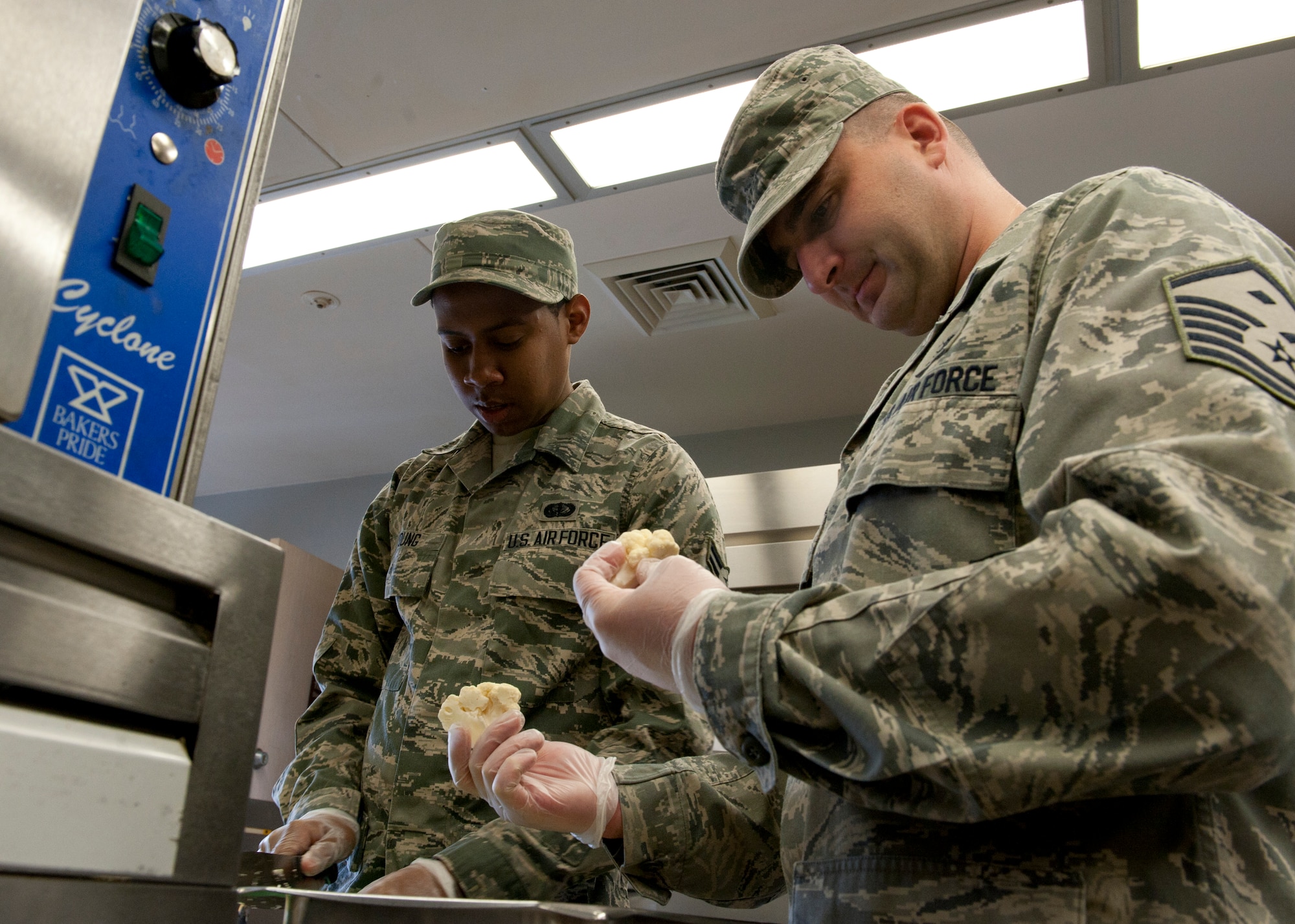 Master Sgt. Wayne Theunissen, 92nd Force Support Squadron first sergeant, helps Airman 1st Class Jonathan Young, 92nd FSS food services apprentice, as they prep cauliflower for the lunch service in the Ross Dining Facility at Fairchild Air Force Base, Wash., June 13, 2012. As the first sergeant, Theunissen acts as the principle advisor to the commander on all issues related to the enlisted force. (U.S. Air Force photo by Staff Sgt. Michael Means/Released)  