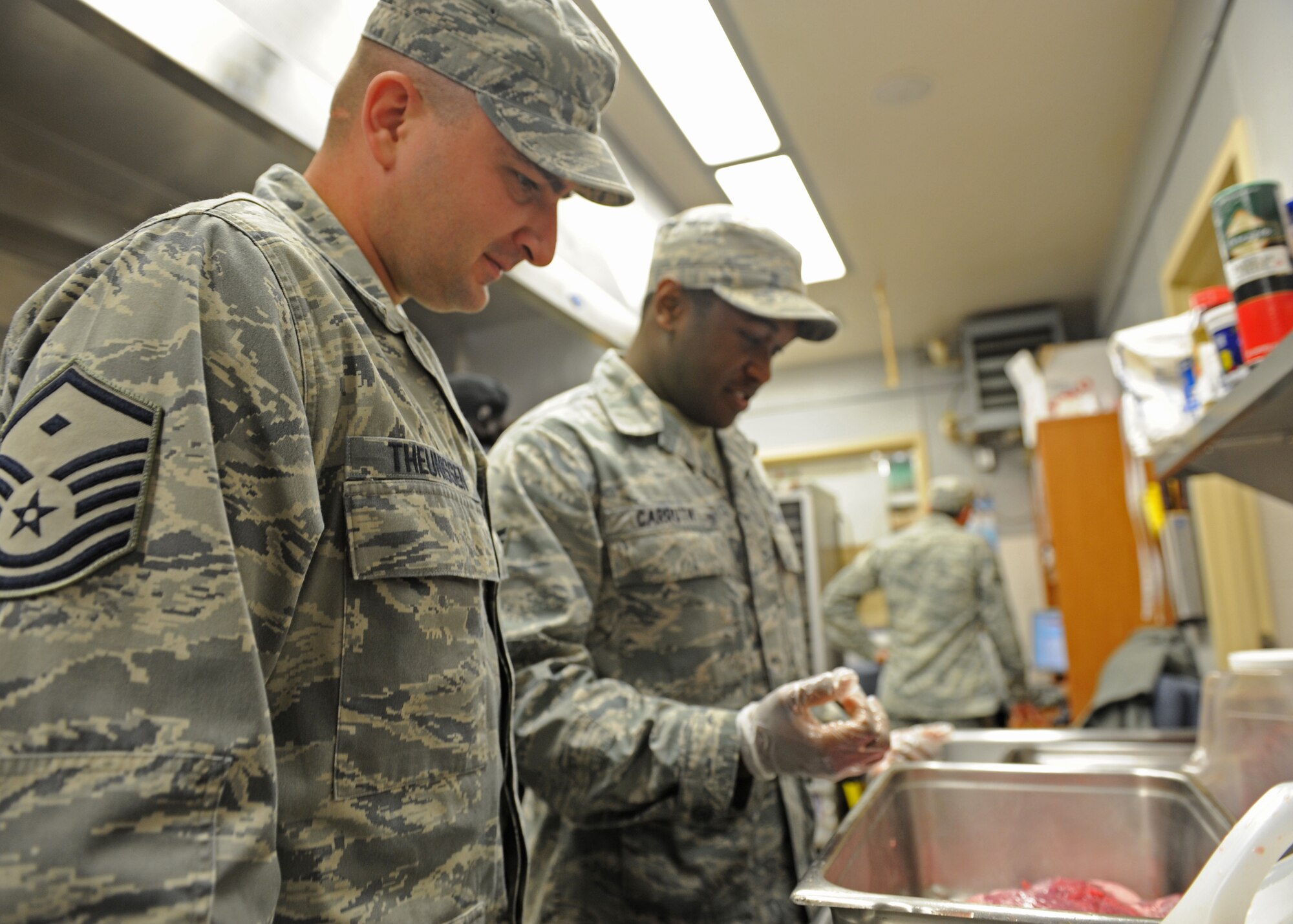 Master Sgt. Wayne Theunissen, 92nd Force Support Squadron first sergeant, speaks to Senior Airman Malcom Carruth, 92nd FSS Ross Dining Facility shift leader, as he preps flank steak at Fairchild Air Force Base, Wash., June 13, 2012. Theunissen took time to visit with his Airmen during the renovation of the dining facilities. (U.S. Air Force photo by Staff Sgt. Michael Means/Released)  