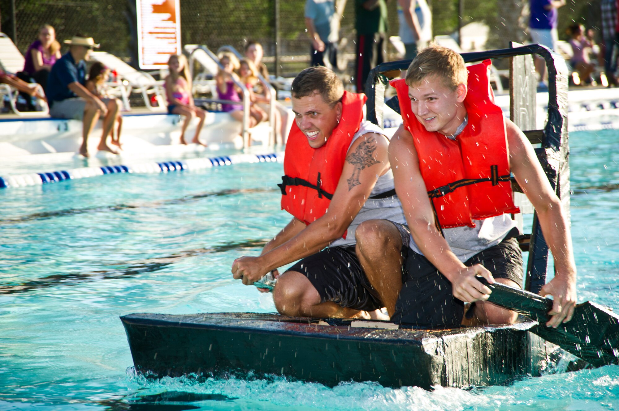 Senior Airman Justin Kent and Airman Basic Gerad Lee compete for Team X-Ray, representing the 81st Diagnostics and Therapeutics Squadron, at the cardboard boat regatta on June 16, 2012, at the Triangle Pool, Keesler Air Force Base, Miss. Team X-Ray advanced to the tie-breaker round. Participants raced boats made only of cardboard and tape, crewed by two team members.  Team SeaBee took first place in the event. (U.S. Air Force photo by Adam Bond)