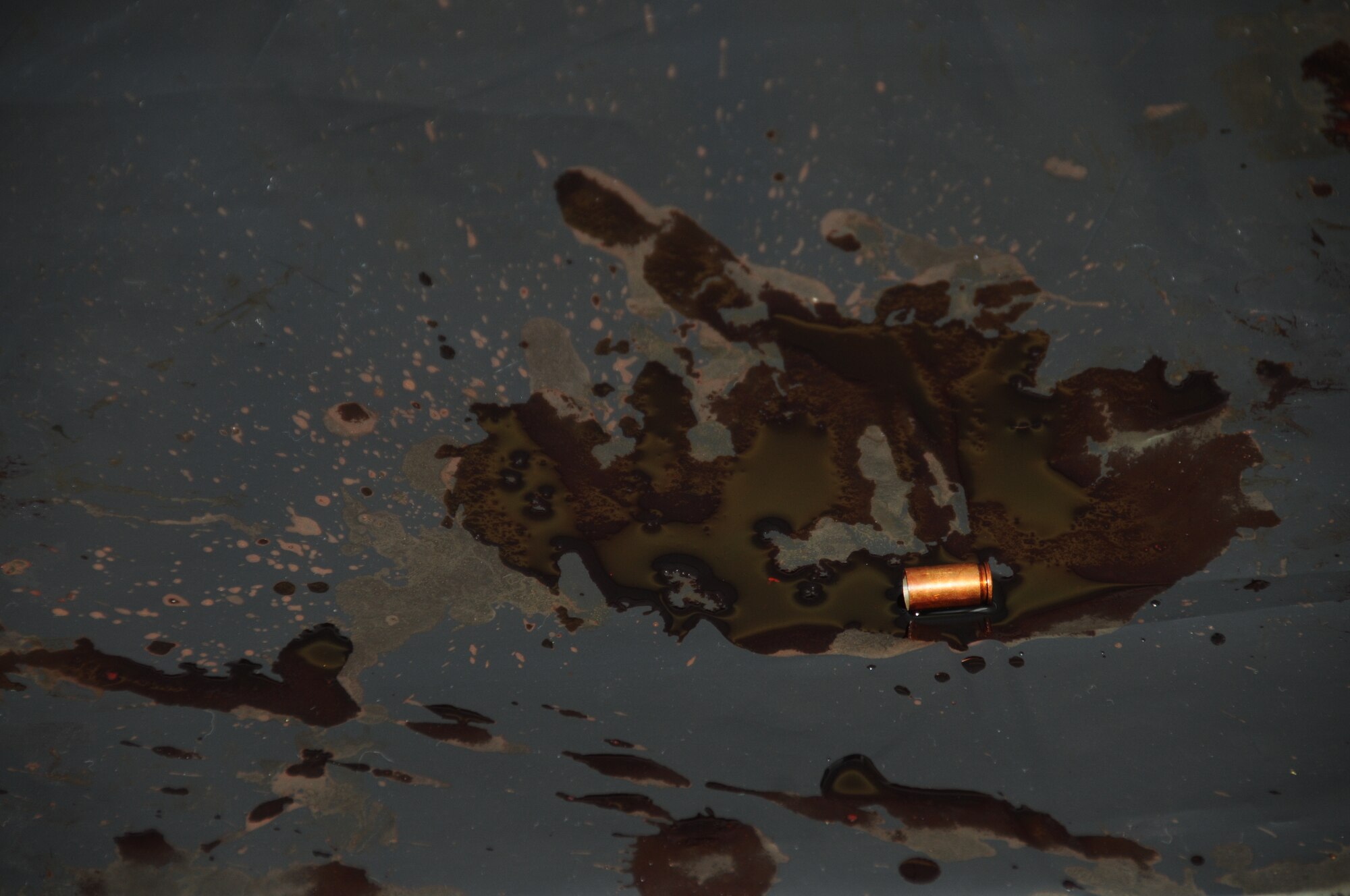 A puddle of fake blood and an empty bullet shell is left on display during Keesler's active shooter exercise, June 12, 2012, at the Arnold Annex, Keesler Air Force Base, Miss.  The scene will remain uncontaminated throughout the scenario so that investigators can continue their job. The two-day exercise consisted of a lone gunman opening fire with four people killed and 32 injured. The exercise tested the base's ability to respond and recover from a mass casualty event.  (U.S. Air Force photo by Kemberly Groue)