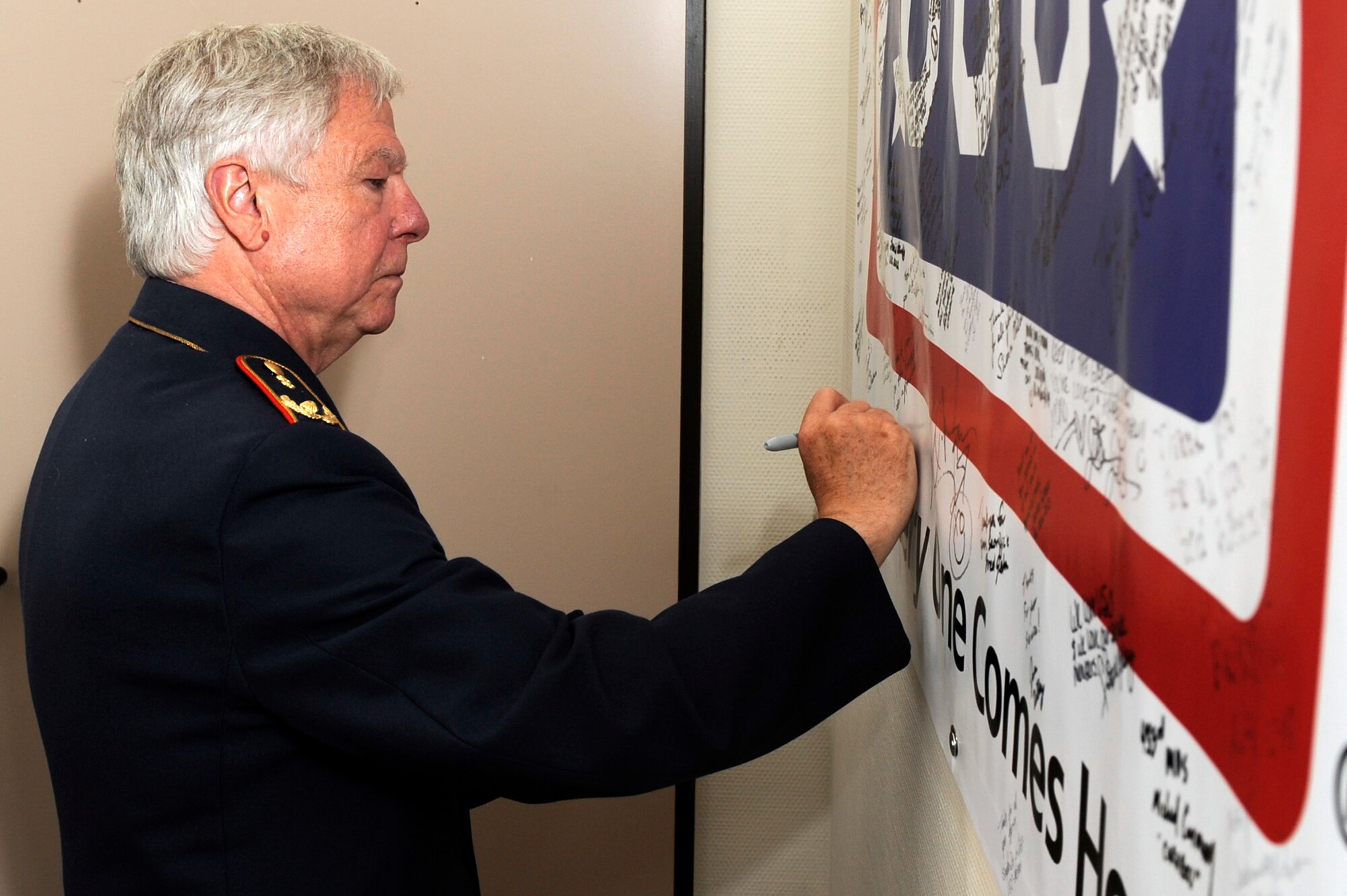 German air force surgeon general (Brig. Gen.) Joerg Binneweis, signs a wounded warrior banner at the Contingency Aeromedical Staging Facility at Ramstein Air Base, Germany, June 13, 2012. This visit gave the German air force general the opportunity to observe the hard work of the U.S. service members who ensure wounded warriors receive world-class care. (U.S. Air Force photo/Senior Airman Aaron-Forrest Wainwright)
