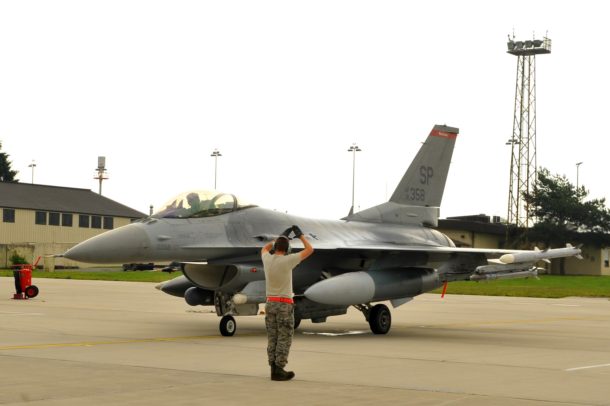 SPANGDAHLEM AIR BASE, Germany – Airman 1st Class Joshua Berard, 480th Aircraft Maintenance Unit crew chief, signals an F-16 Fighting Falcon pilot to proceed during a standard aircraft launch procedure on Ramp 4 here June 19. The 480th AMU plays a vital role in supporting the F-16’s combat training mission, which prepares them for regional defense and air superiority. (U.S. Air Force photo by Airman 1st Class Dillon/Released)