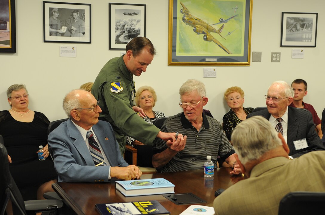 Col. Ken Rizer, 11th Wing/Joint Base Andrews commander, gives a commander's coin of excellence to 11th Bombardment Group members during a dedication of a new conference room in the William A. Jones III Building here on May 19. John Coyle, former B-24 no gunner, Jack Worrle, former B-24 tail gunner, and Mel Engeman, former B-24 pilot, attended the dedication and recieved coins. The new conference room is dedicated to Brig. Gen. LaVerne "Blondie" Saunders, former 11th Bombardment Group commander. Saunders let the "Grey Geese" in the early years of World War II and was one the few pilots to get a bomber into the air during the attack on Pearl Harbor. 