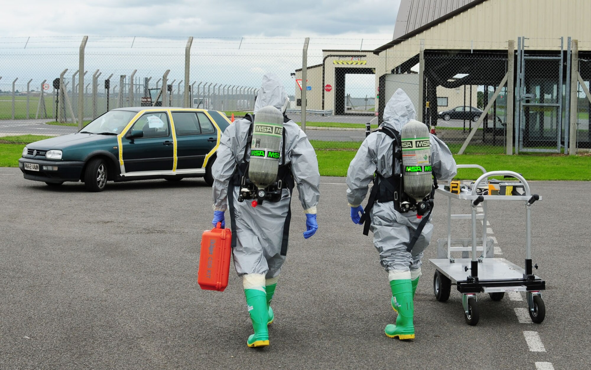 RAF MILDENHALL, England – Airman 1st Class Joshua Foxworth and Staff Sgt. Jesse Furse, both 100th Civil Engineer Squadron Emergency Management, wear Level-B chemical protection suits as they head towards a suspect vehicle during a hazardous materials response exercise June 12, 2012. The two response-team members performed air sampling and determined the chemical hazard to be (simulated) hydrogen sulfide. (U.S. Air Force photo/Karen Abeyasekere)