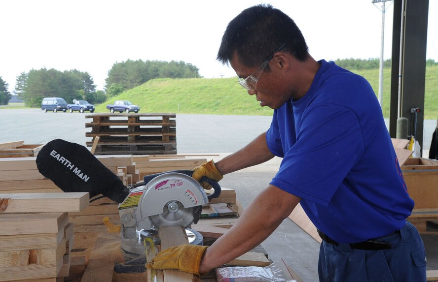 Kazunari Hieda, Japanese palletization team member, cuts wood with a power saw at Misawa Air Base, Japan, June 19, 2012. The team came from Hiroshima, Japan to assist the 35th Maintenance Squadron ammunitions Airmen pack excessive unserviceable munitions. (U.S. Air Force photo by Airman Kenna Jackson/Released)