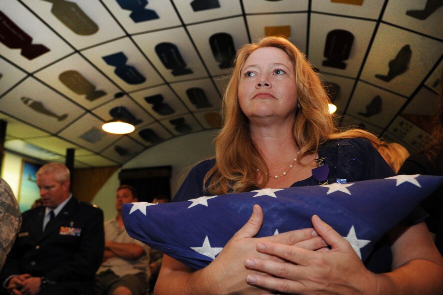 Cornelia Brantley holds the flag presented to her husband Chief Master Sgt. John Brantley during his retirement ceremony, May 18, 2012, at Barksdale Air Force Base, La. As a 24-year military spouse, she endured many separations and raised four children as her loved one served around the world. Now, two of her kids are also serving in the Air Force. (U.S. Air Force photo/Senior Airman Brigitte N. Brantley)