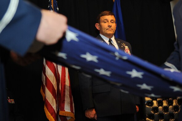 Chief Master Sgt. John Brantley watches in silence as a flag is unfolded by Honor Guard members during his retirement ceremony, May 18, 2012, at Barksdale Air Force Base, La. Once refolded, the flag was presented to Brantley on behalf of the President of the United States in appreciation for his 27 years of service. (U.S. Air Force photo/Senior Airman Brigitte N. Brantley)