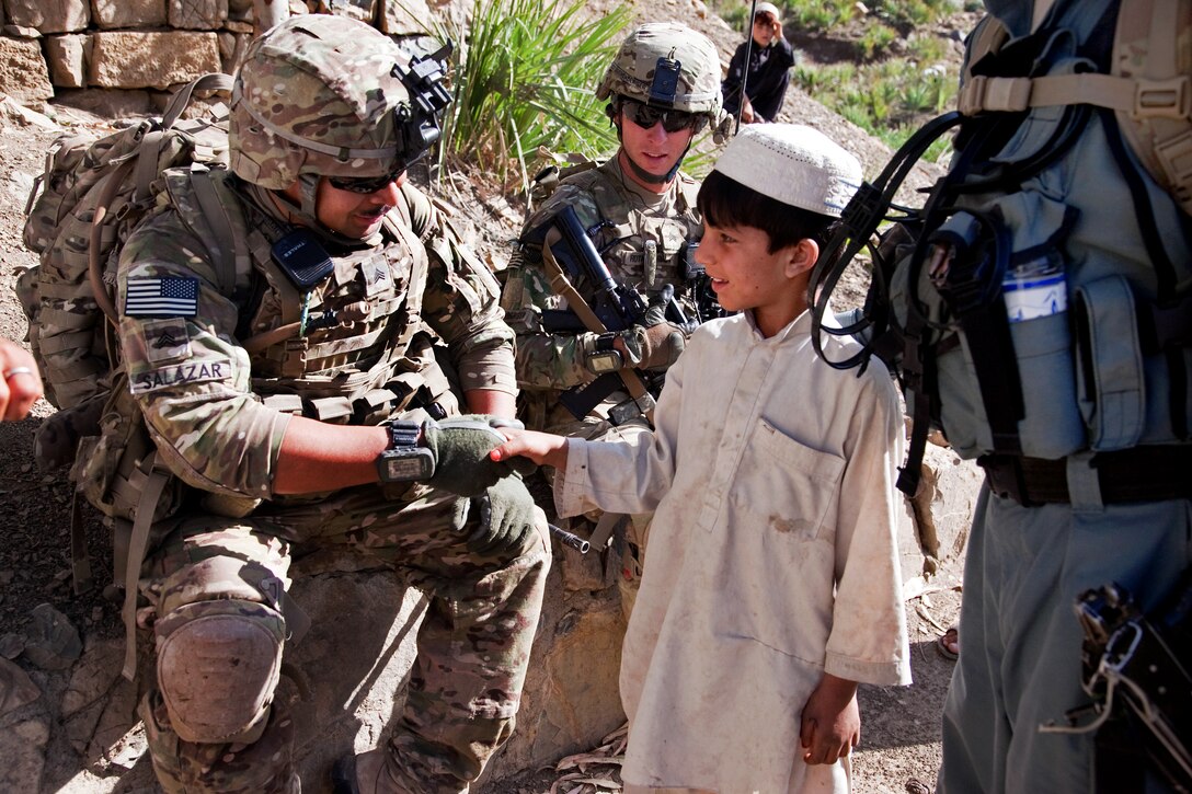 U.S. Army Sgt. Robert Salazar shakes hands with an Afghan boy in Loy Murghoz in Afghanistan's Khowst province, June 8, 2012. Salazar, a team leader, is assigned to 2nd Battalion, 377th Parachute Field Artillery Regiment.
