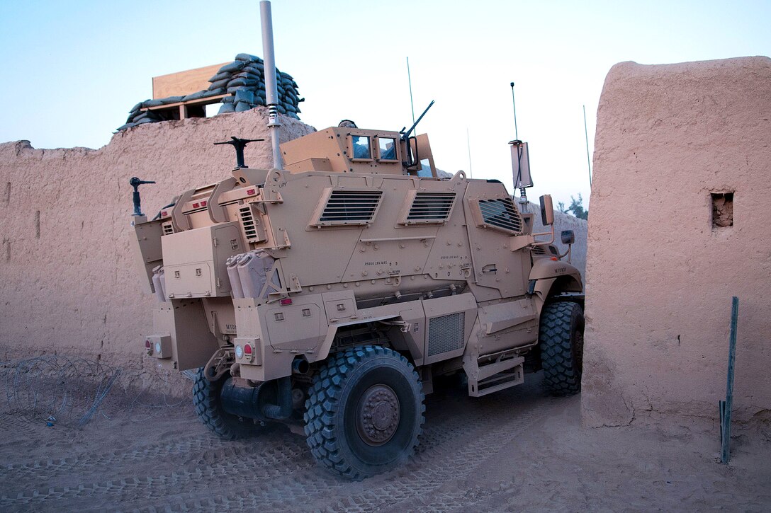 A mine-resistant, ambush-protected vehicle passes through a narrow opening between walls before entering Joint Security Station Hasan in the Gilan district in southern Afghanistan's Ghazni province, June 11, 2012.