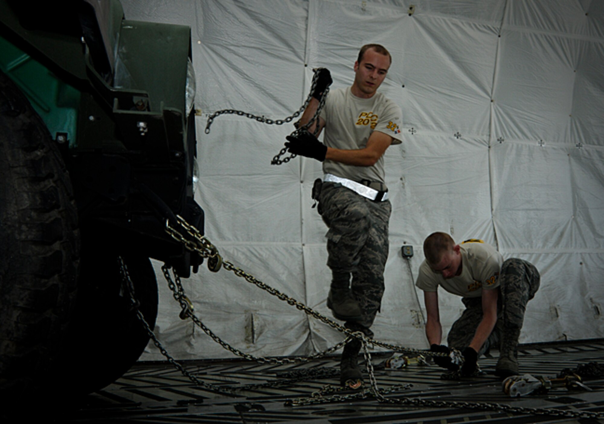 Senior Airmen Michael Smith and Jonathan Hogan, 32nd Aerial Port Squadron air transportation specialists, secure a Humvee to the floor of a C-5 Galaxy static as part of a cargo restraint exercise during the second day of the Port Dawg Challenge competition held at Dobbins Air Reserve Base, Ga., June 20, 2012. The cargo restraint exercise requires teams to calculate the restraints required when equipment is shipped on cargo aircraft. (U.S. Air Force photo by Senior Airman Joshua J. Seybert/Released)