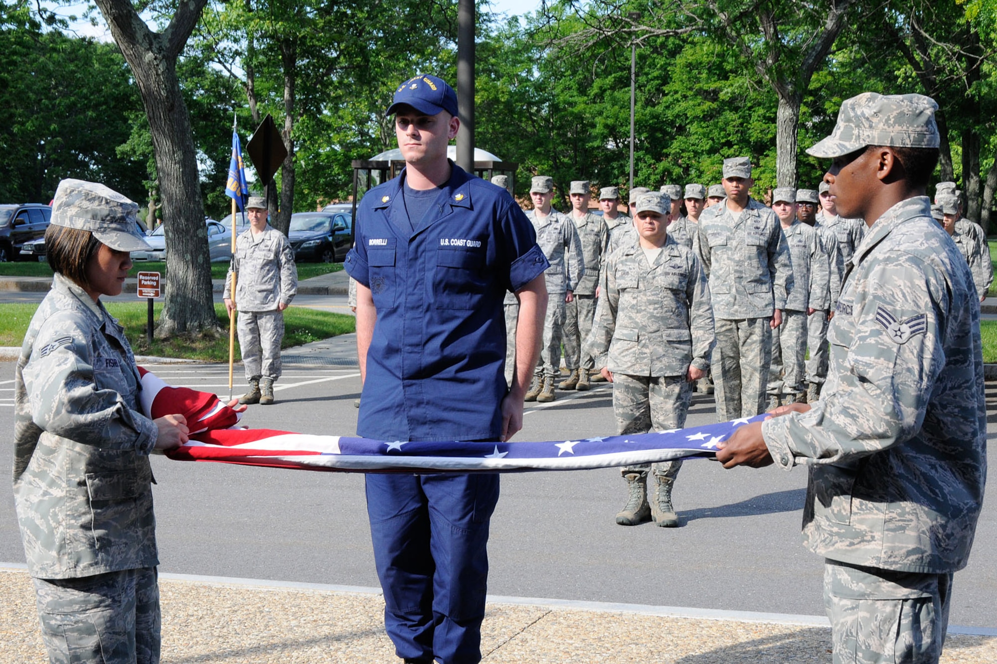 HANSCOM AIR FORCE BASE, Mass. – Airman Leadership School students (from left to right) Senior Airman Joanna Fisher, Petty Officer Nicholas L. Borrelli and Senior Airman Paul A. Hollis fold the flag as members of the 66th Air Base Group stand at attention during a formal retreat ceremony in front of Building 1606 June 14. The ceremony was part of the base’s Flag Day commemoration. (U.S. Air Force photo by Linda LaBonte Britt)