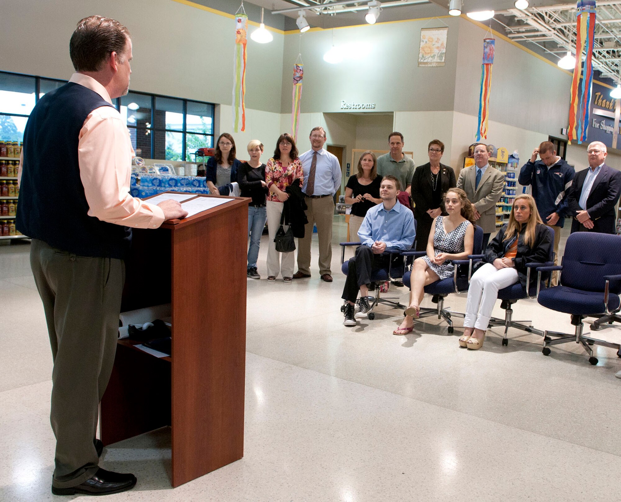 HANSCOM AIR FORCE BASE, Mass. - Clyde Nolen, commissary store director, speaks to members gathered at the commissary prior to awarding five scholarships as part of the 2012 Fisher House Scholarships for Military Children Program June 13. Scholarship recipients in attendance were (seated left to right) James Johnston, Sarah Witzig and Natalie Devine. Joseph Putko and Madison Granger also received scholarships. The program was created to recognize military families’ contributions to the readiness of U.S. armed forces and the commissary’s role in the military community. (U.S. Air Force photo by Mark Wyatt)