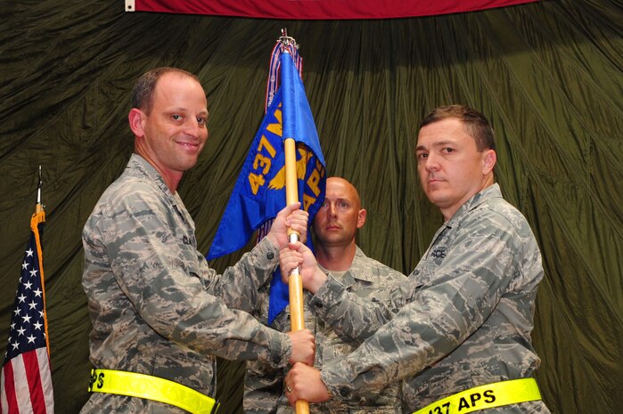 Colonel James Clavenna, 437th Maintenance Group commander, passes the squadron guidon to Maj. Christopher Carmichael, 437th Aerial Port Squadron commander, during the 437th APS change of command ceremony at Joint Base Charleston - Air Base, S.C, June 19, 2012. The passing of the unit guidon symbolizes the changing of a command. (U.S. Air Force photo/ Airman 1st Class Chacarra Walker)