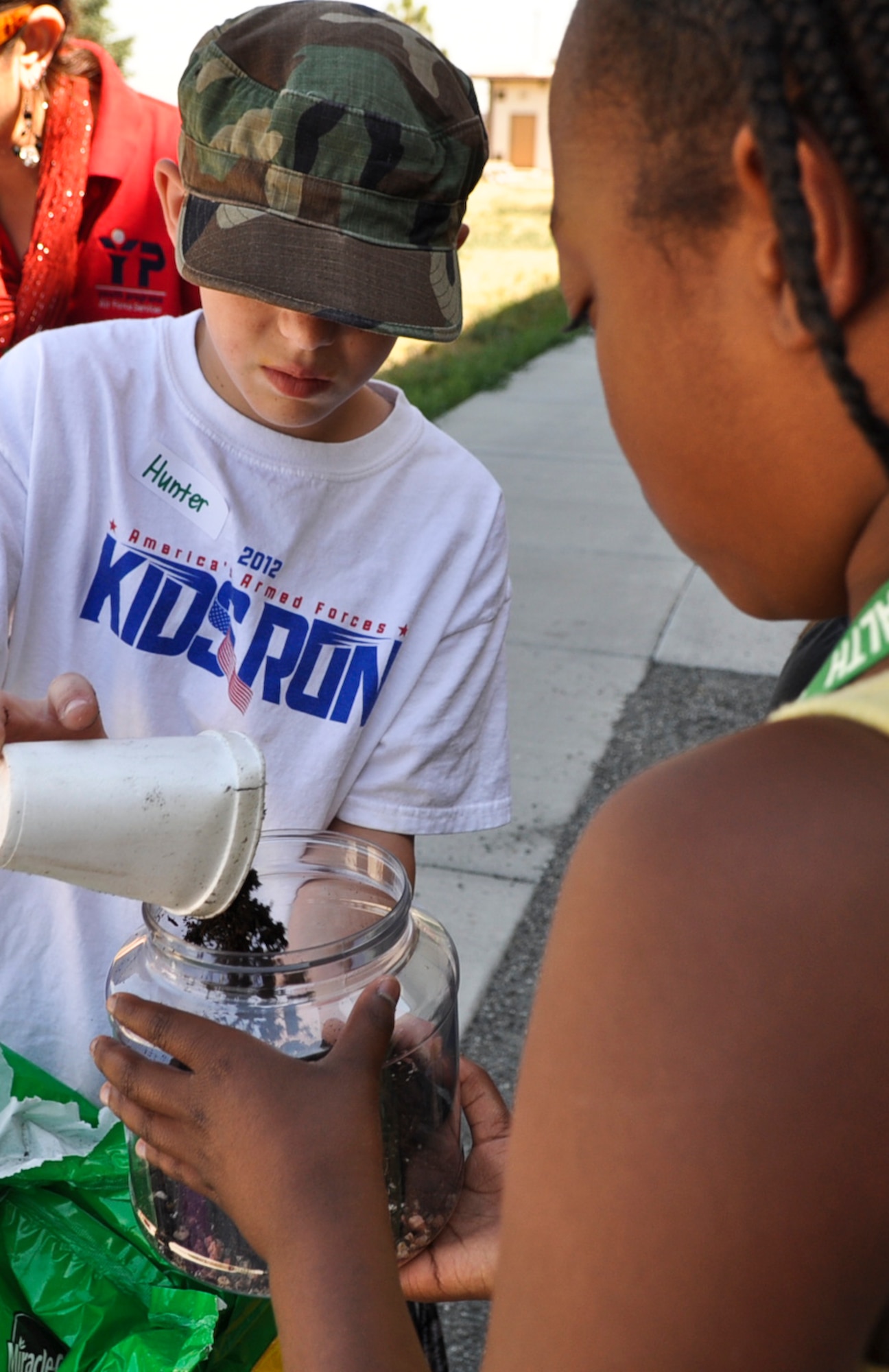 BUCKLEY AIR FORCE BASE, Colo. – Hunter Skowronski dumps soil into Kyla Barnes terrarium June 19, 2012. The Buckley Youth Center had 26 children participate in their 4-H Jr. Science Explorers Club, in which they learned about the outdoors and the importance of conserving it. (U.S. Air Force photo by Senior Airman Christopher Gross)