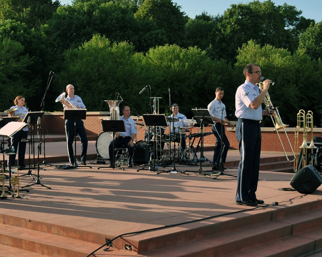 Airman First Class Benjamin Huseby addresses the audience at a Brass in Blue performance - part of the Heartland of America Band's "Sunday's on Parade" concert series on the Offutt Air Force Base Parade Field