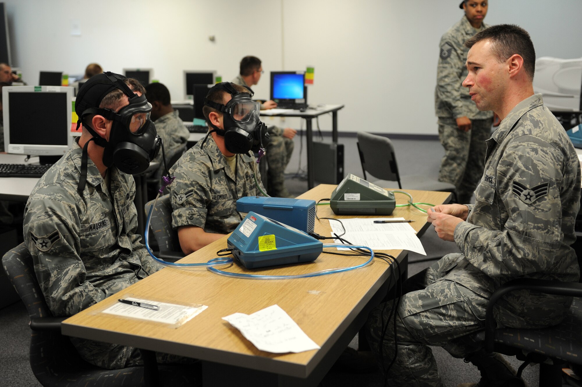 U.S. Air Force Senior Airman Donary Scully, right, 35th Aerospace Medicine Squadron bioenvironmental engineer craftsman, instructs Airman 1st Class Daniel Hauskins, left, 35th Security Forces Squadron patrolman, and Airman 1st Class Jacob Lombardi, 35th Fighter Wing Public Affairs broadcaster, on what to do during their quantitative fit-tests at Misawa Air Base, Japan, June 20, 2012. Airmen conduct several exercises during the QNFT to ensure their gas masks fit properly. (U.S. Air Force photo by Airman 1st Class Kia Atkins/Released)