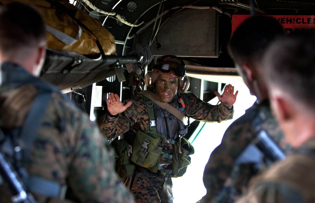 Marine Corps Gunnery Sgt. Shawn D. Decker signals his Marines to guide an inflatable raft out the back of a CH-53E Super Stallion helicopter and into the water off the North Carolina coast as part of Operation Mailed Fist, June 18, 2012. 