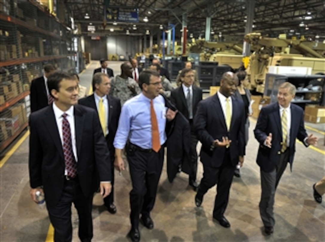 Deputy Secretary of Defense Ashton B. Carter (blue shirt) is given a tour of the Vehicular Integrated Solutions Facility during a visit to Joint Base Charleston in Charleston, S.C., June 18, 2012.  Carter was accompanied on the tour of the facility by Space and Naval Warfare Systems Command Executive Director Chris Miller (left), Rep. Tim Scott (second from right), and Sen. Lindsey Graham (right).  