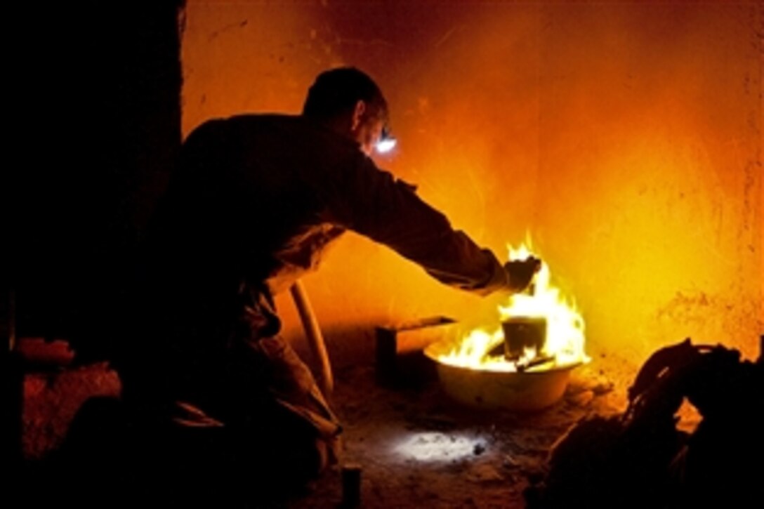 A U.S. paratrooper heats noodles over a fire on Joint Security Station Hasan in the Gilan district in southern Afghanistan's Ghazni province, June 12, 2012. The soldier is assigned to the 82nd Airborne Division's 1st Battalion, 504th Parachute Infantry Regiment, 1st Brigade Combat Team.