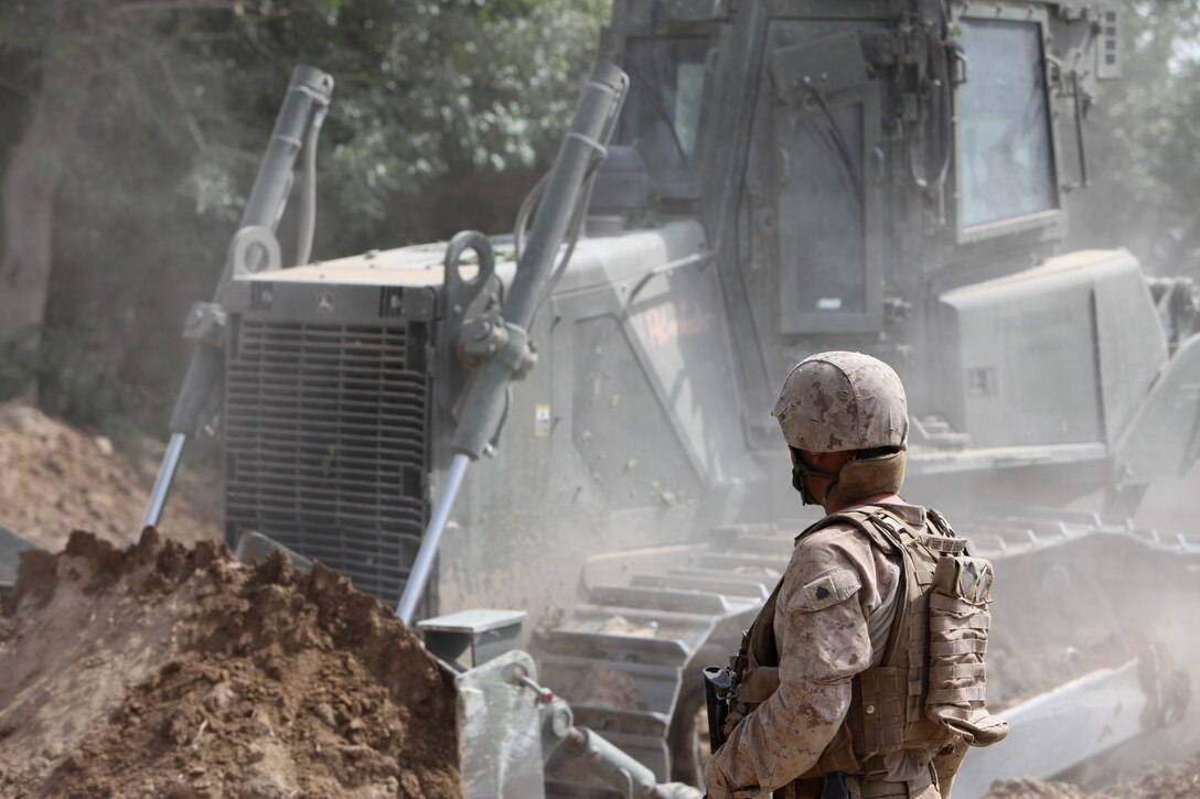 A heavy equipment operator from 8th Engineer Support Battalion, 1st Marine Logistics Group (Forward) guides a Medium Crawler Tractor during the construction of a culvert at a village stability platform manned by special operations forces, June 21. The area proved to be kinetic as enemy activity was high. Several improvised explosive devices were found or struck along the route to the VSP, and insurgents also engaged Charlie Company with small arms fire.