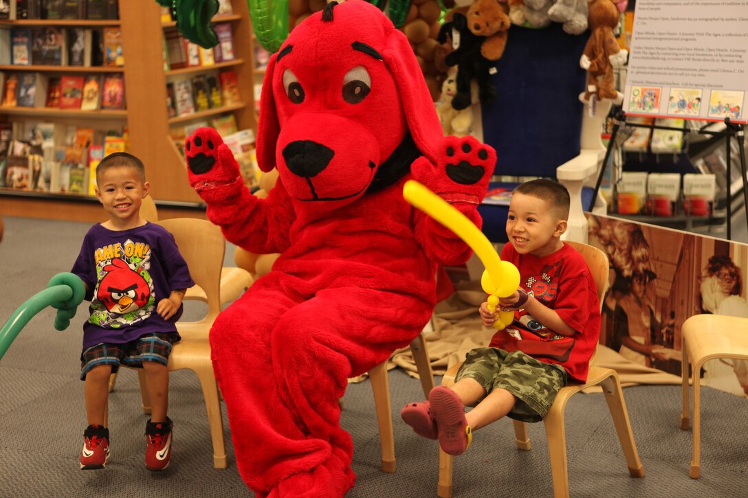 Two boys pose for a picture with author Glenna C. Orr dressed as Clifford the Big Red Dog during a book fair at the Marine Corps Exchange aboard Marine Corps Base Camp Lejeune June 16. Children were attracted to the bright red costume and kept visiting Orr throughout the day to hear her read some of her stories.