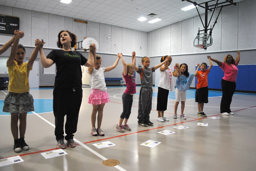 Dance camp participants raise their hands and take a bow after performing their last number to wrap up a week of dancing at the Youth Center on June 15. The finale included dancing, singing and piano performances by participants. Brynne Shipman, second from left, and her assistant, Jennifer Hawkins, far right, taught 14 children ages 7 to 18, country western, hip hop, ballroom and swing dancing. (U.S. Air Force photo/Airman 1st Class Katrina Heikkinen)