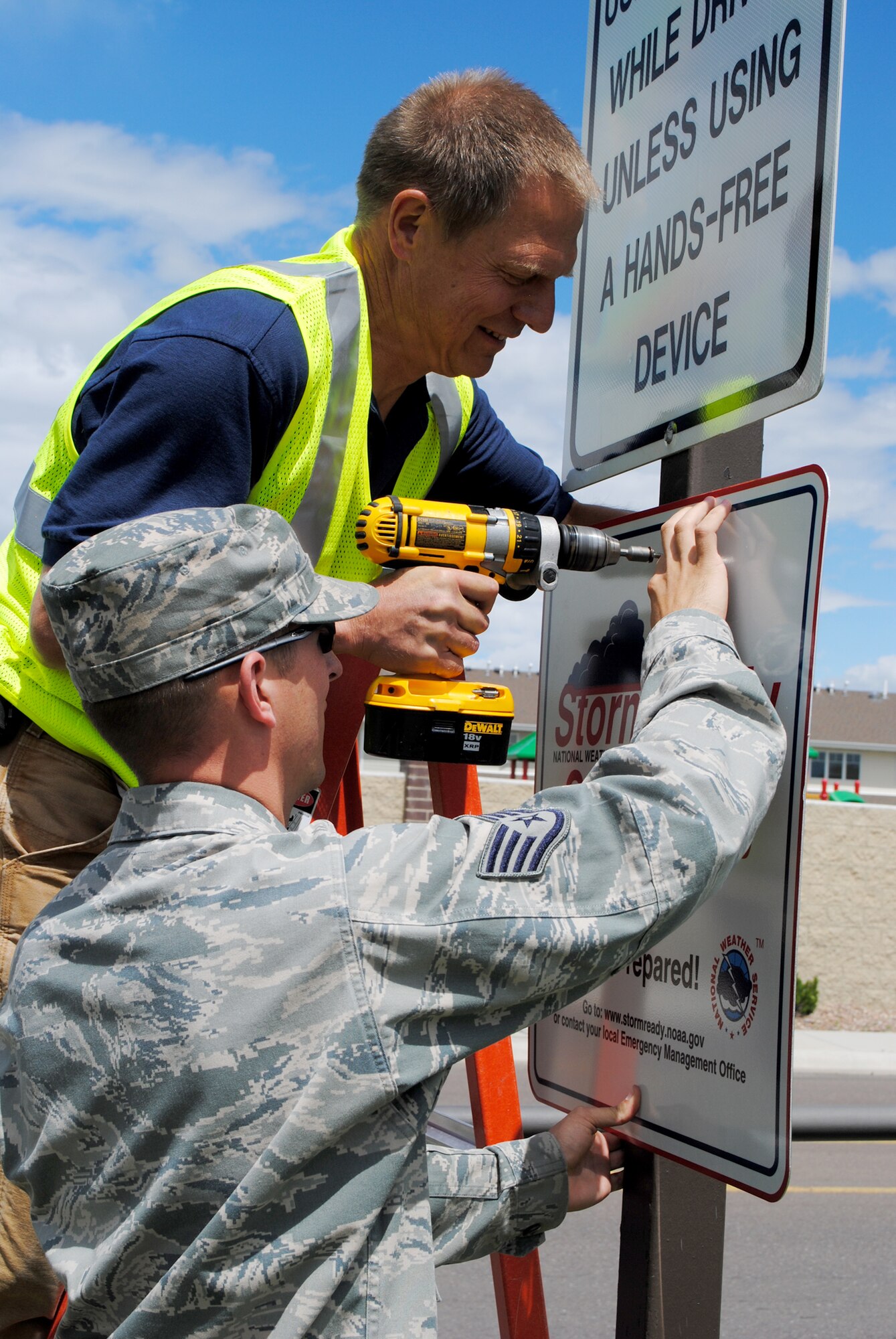 Staff Sgt. Nathan Sisk, 341st Civil Engineer Squadron emergency operations technician, and Dave Chandler, 341st CES sign shop member, hang a StormReady® sign on a post near the base’s front gate.  This StormReady® certification properly signifies that Malmstrom Air Force Base has the capabilities to keep it’s community aware of and safe from significant inclement weather changes.  (U.S. Air Force photo/Airman 1st Class Cortney Paxton)