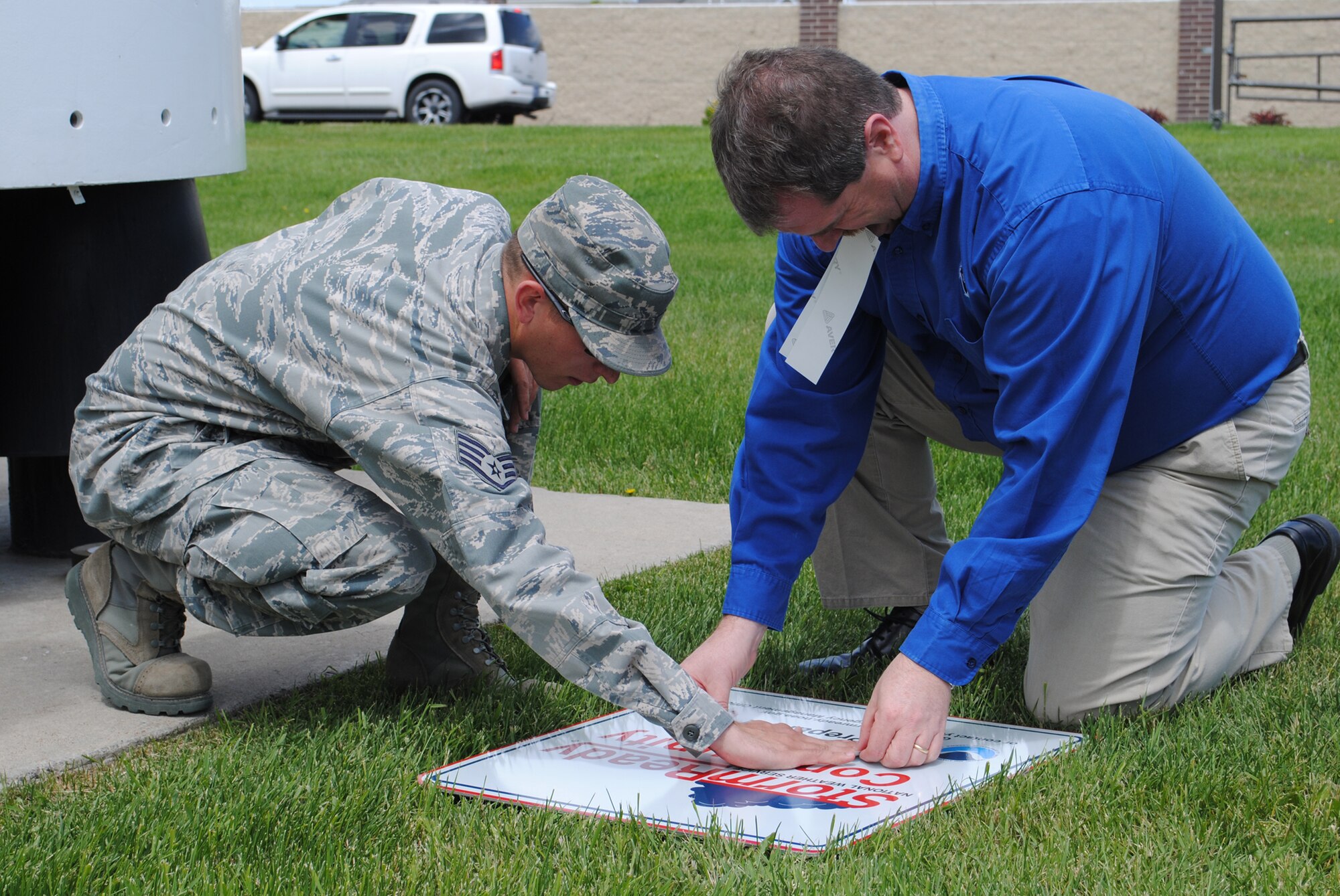 Staff Sgt. Nathan Sisk, 341st Civil Engineer Squadron emergency operations technician, helps Michael Mercer, National Weather Service member, place date stickers onto Malmstrom’s StormReady® signs.  The base was certified as StormReady® on May 3 and two signs will be posted at each gate respectively signifying the accomplishment.  (U.S. Air Force photo/Airman 1st Class Cortney Paxton)