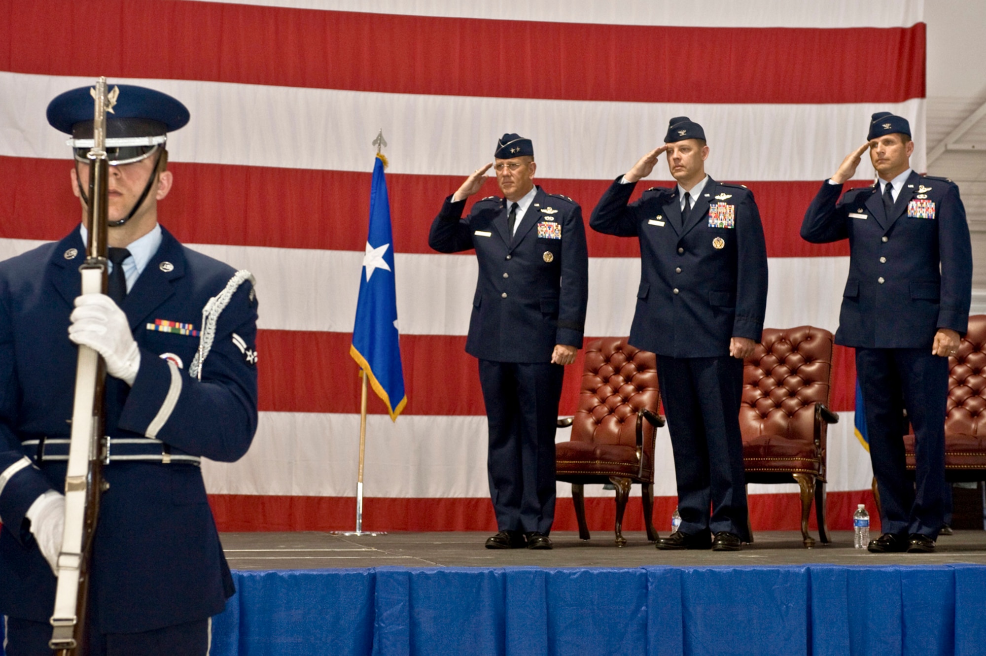 (left to right on podium) Maj. Gen. Bill Hyatt, U.S. Air Force Warfare Center commander, Brig. Gen. (sel) Steven Garland, 99th Air Base Wing outgoing commander, and Col. Barry Cornish, 99th Air Base Wing incoming commander, render a salute as the Nellis Honor Guard posts the colors during the 99th ABW Change of Command June 15, 2012, at Nellis Air Force Base, Nev. The commanders highlighted their appreciation for friends and family in attendance, as well as the generous support Nellis has received from the Southern Nevada community. (U.S. Air Force photo by Airman 1st Class Daniel Hughes)
