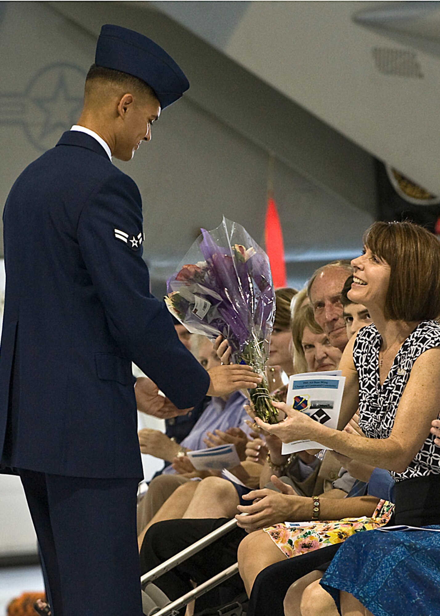 Paula Garland, wife of Brig. Gen. (select) Steven Garland, 99th Air Base Wing outgoing commander, receives a bouquet of flowers from Airman 1st Class Michael Camarillo, 99th Logistics Readiness Squadron during the 99th Air Base Wing Change of Command June 15, 2012, at Nellis Air force Base, Nev. Garland will be assuming command of the 36th Wing, Andersen Air Force Base, Guam. (U.S. Air Force photo by Staff Sgt. Christopher Hubenthal)