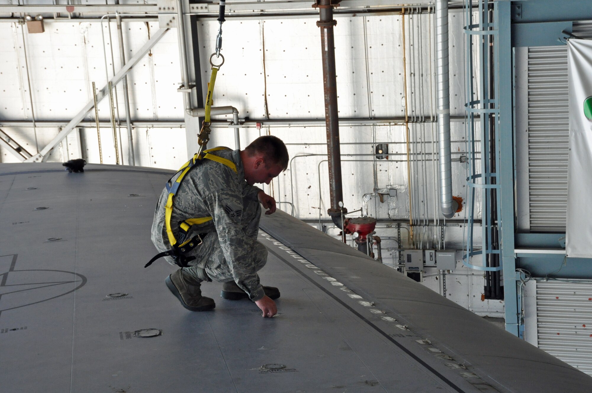 Senior Airman Robert Gay, 60th Aircraft Maintenance Squadron crew chief, demonstrates a new harness system 13 June in the 60th AMXS Home Station Check dock. The new harness system was implemented after an Air Force Smart Operations for the 21st Century Rapid Improvement Event discovered the old harness system to be obsolete. (U.S. Air Force photo/ Staff Sgt. Patrick Harrower)