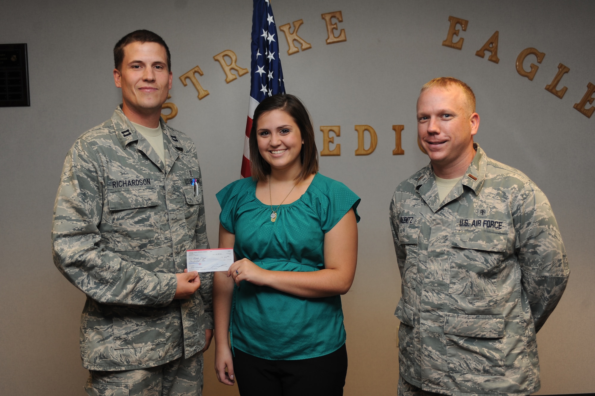 Brooke Mayo, (middle) daughter of Master Sgt. Ronnie Mayo, is presented a scholarship by U.S. Air Force Capt. Jordan Richardson and 2nd Lt. Aaron Valentz in the 4th Medical Group medical treatment facility on Seymour Johnson Air Force Base, N.C., June 20, 2012. Brooke was awarded the $500 Company Grade Officer’s Council scholarship after writing a one-page essay explaining her advanced education plans. Richardson, 4th Medical Operations Squadron physical therapy element chief, hails from Humboldt, Tenn. Valentz, 4th Medical Support Squadron medical readiness flight commander, is a native of Warren, Ohio. Ronnie, 4th Communications Squadron equipment control officer, and Brooke, are from Goldsboro, N.C. (U.S. Air Force photo/Airman 1st Class John Nieves Camacho/Released)