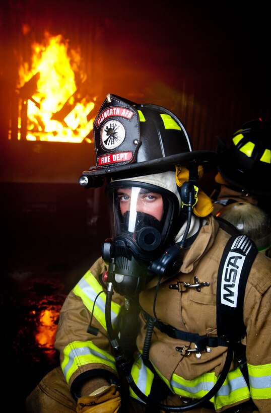Airman 1st Class James Blair, 28th Civil Engineer Squadron fire protection specialist, catches his breath after battling multiple fires as part of a simulated fire exercise at Ellsworth Air Force Base, S.D., June 18, 2012. The simulated structural fires allow firefighters to safely practice extinguishing fires in a controlled training environment. (U.S. Air Force photo by Airman 1st Class Zachary Hada/Released)