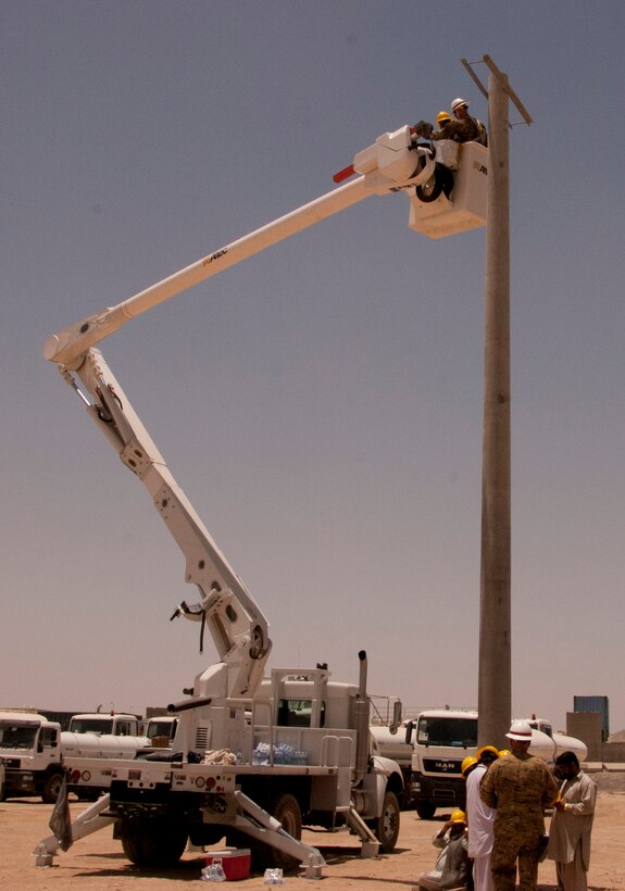 KANDAHAR AIRFIELD, Afghanistan — Sgt. Gabriel Akonom, 249th Prime Power Battalion, U.S. Army Corps of Engineers Afghanistan Engineer District-South, shows an Afghan technician from Da Afghanistan Breshna Sherkat, Afghanistan's electric utility company, how to maneuver the work platform on one of the two "bucket trucks" donated to the utility by the United States.