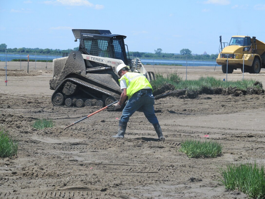 NEW YORK — A Burke Environmental contractor working on the site, finalizing the re-planting of a hummock. He is back filling dirt around the plant and then he will rake the area around it until it is smooth.

 