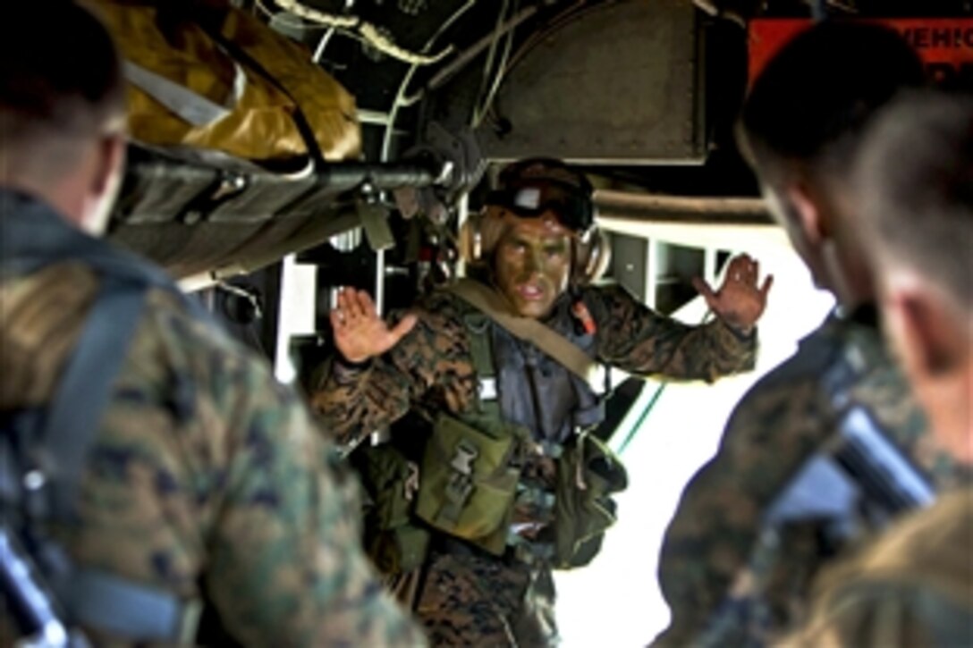 Marine Corps Gunnery Sgt. Shawn D. Decker signals his Marines to guide an inflatable raft out the back of a CH-53E Super Stallion helicopter into the water off the North Carolina coast as part of Operation Mailed Fist, June 18, 2012. 