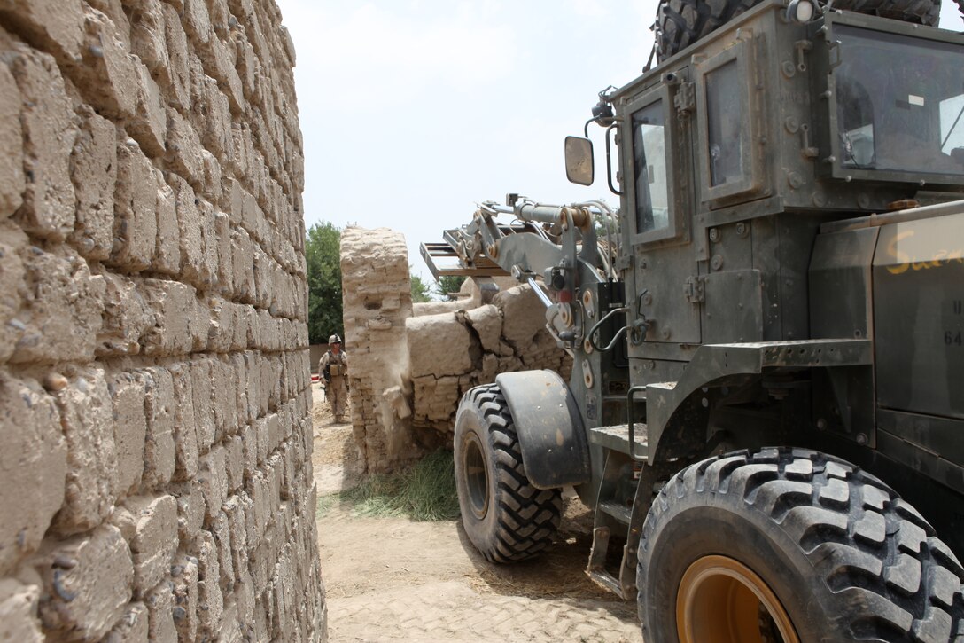 A heavy equipment operator from 8th Engineer Support Battalion, 1st Marine Logistics Group (Forward) uses a Tractor, Rubber tired, Articulated steering, Multi-Purpose vehicle to destroy a section of inner compound wall at a village stability platform manned by special operations forces, June 21.  The area proved to be kinetic as enemy activity was high. Several improvised explosive devices were found or struck along the route to the VSP and insurgents also engaged Charlie Company, 8th ESB with small arms fire.