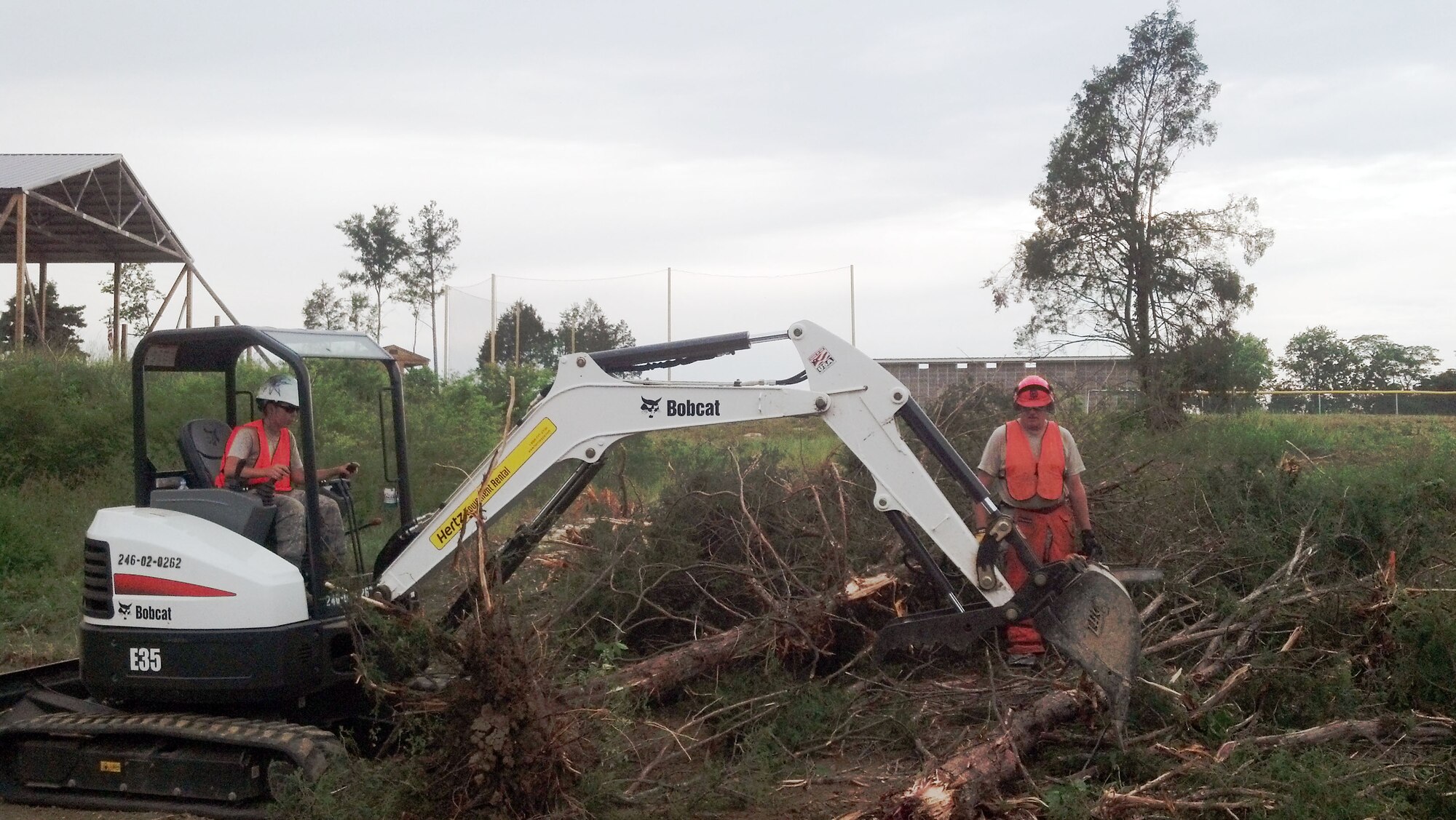 Airmen clear trees with a mini excavator in May at Riverside Christian Acadamy, Fayetteville, Tenn.  The school suffered hundreds of lost trees and damage to several structures prompting civil engineers from Luke AFB, Ariz., Hill AFB, Utah, and Grissom Air Reserve Base, Ind., to respond.
