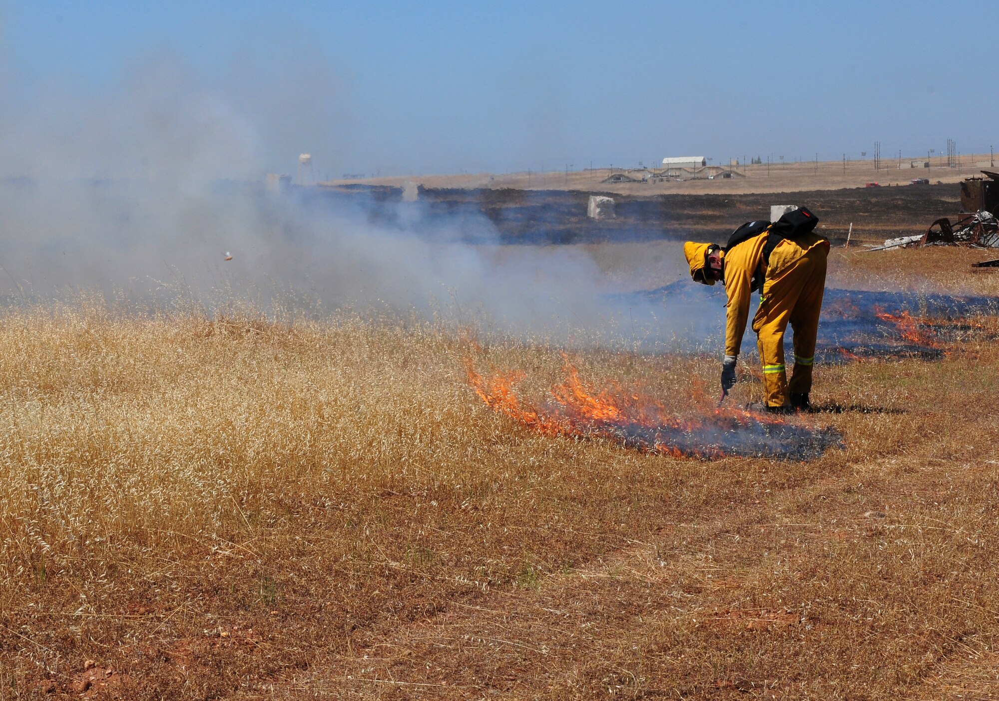 Airman 1st Class Sean Russell, 9th Civil Engineering Squadron firefighter, uses a flare to burn the remaining unburned patches of grassland during the prescribed burn of the M60 machine gun range at Beale Air Force Base, Calif., June 19, 2012. Team Beale firefighters often support local fire departments during the fire season. (U.S. Air Force photo by Senior Airman Allen Pollard/Released)